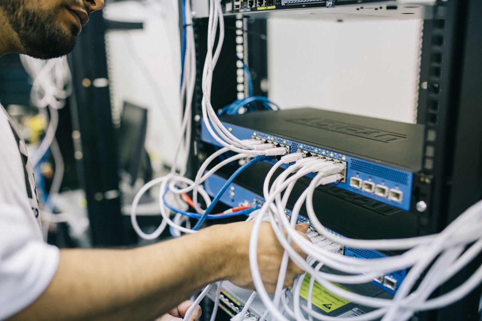 An engineer working on network cabling in an equipment rack.